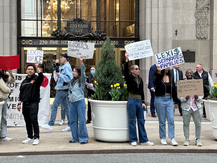 A group of people standing in front of 230 Park Avenue holding various signs that read, “LEXIS loves ICE”, “LEXIS, SHAME ON YOU!”, “LEXIS SURVEILS SO ICE CAN DETAIN & DEPORT. END YOUR CONTRACT WITH ICE!”, “LEXIS SEPARATES FAMILIES”, “LEXIS PROFITS OFF DEPORTATIONS. NO TECH FOR ICE!”