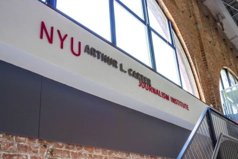 Text reading “N.Y.U. Arthur L. Carter JOURNALISM INSTITUTE” on a white wall with a window above it.