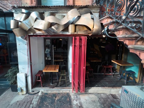 The entrance to a restaurant with red doors and metallic ribbon-like decorations above the door.