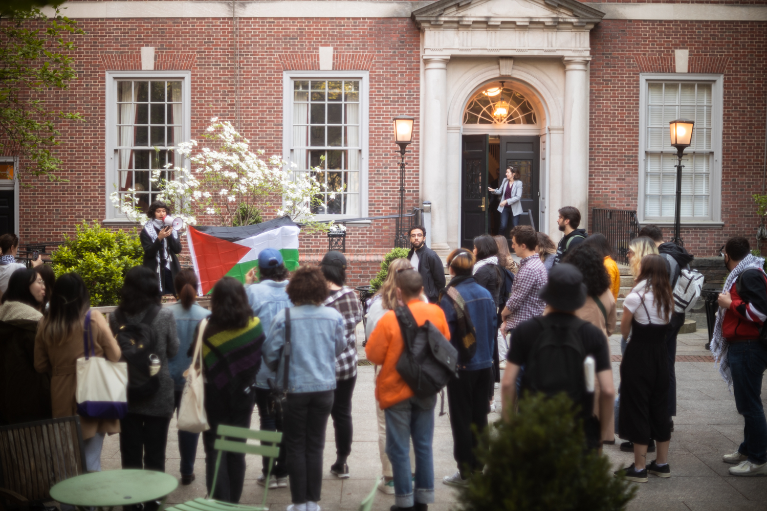 Members of the student group Law Students for Justice in Palestine protest in the Vanderbilt Hall courtyard. A Palestinian flag is being flown in the background.