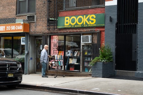 The storefront of Mercer Street Books and Records. Behind the window is a red neon sign that reads “BOOKS.” Above the windows is a green banner with yellow text that reads “Books. Mercer Street Books. 206 Mercer.”