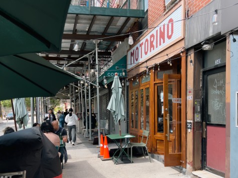 A restaurant with an outdoor dining area. The sign on the entrance reads “Motorino.”
