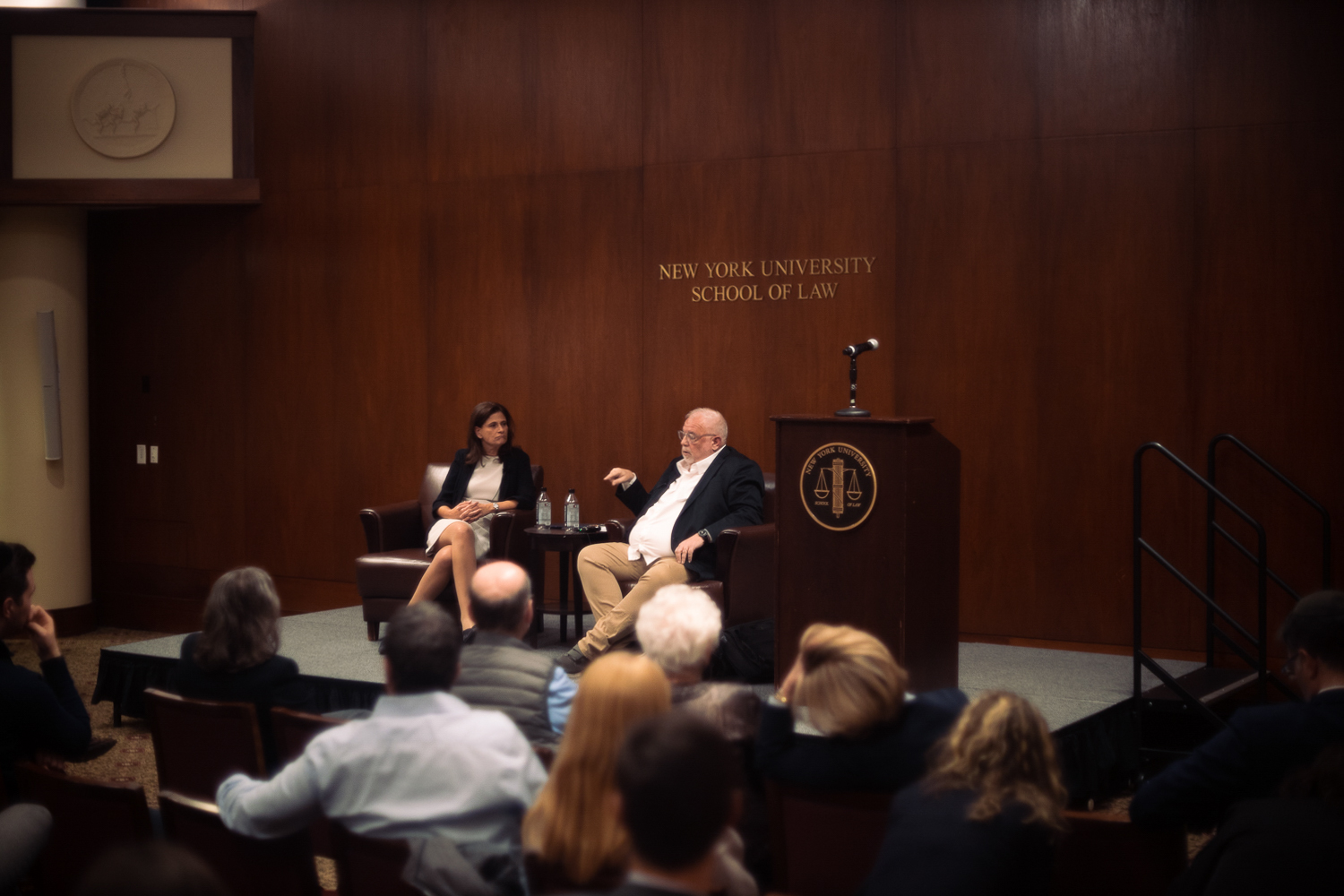 Two speakers sit on a stage in an N.Y.U. Law auditorium. To the left is Michal Cotler-Wunsh. To the right is Robert Howse, a professor.