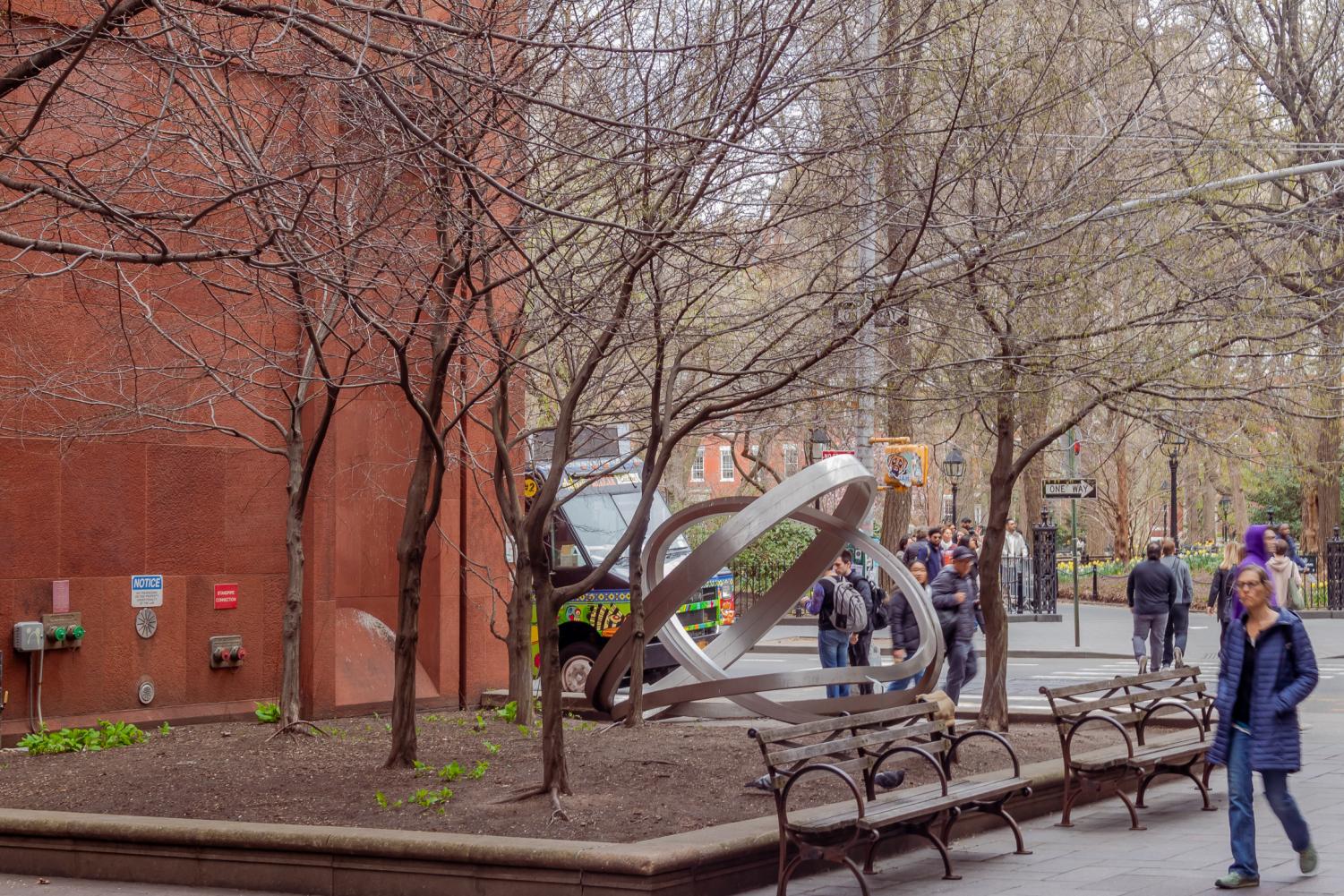 A small garden beside Bobst Library, with trees and benches alongside it.