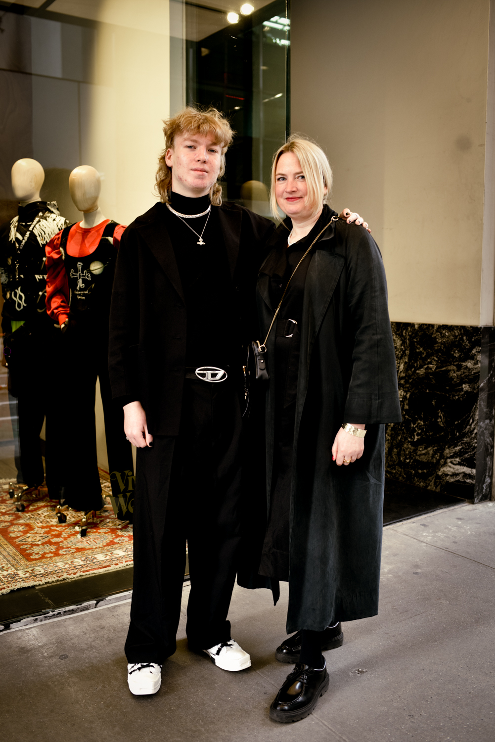 Mother and son Isabel and Titus Duellmann stand together in front of the Vivienne Westwood New York City store. They are wearing all black clothing.