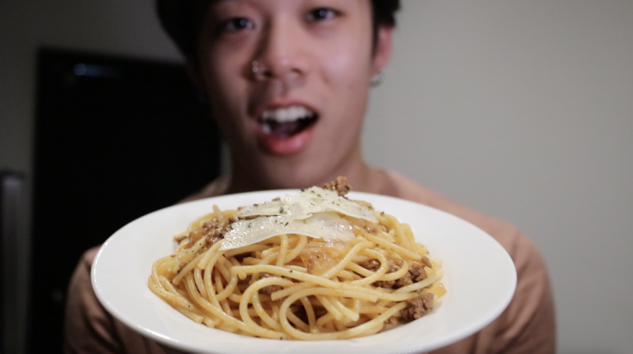 A person holding a plate with spaghetti in it.