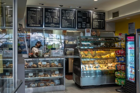 The interior of Bagel Bob’s features silver display cases full of bagels and assorted cream cheese flavors. There is a five part menu above an employee standing by the register.
