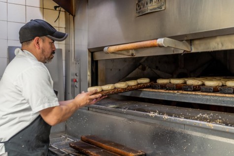 An employee at Bagel Bob’s places uncooked trays of bagels into the large oven.