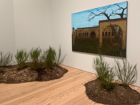 Two exhibits at the Whitney Museum of American Art. There are two patches of grass with dirt on the floor and a painting of a house on the wall.