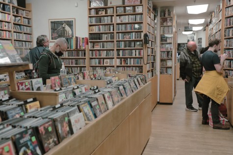 Patrons browse through compact disks placed on wooden shelves and tables.