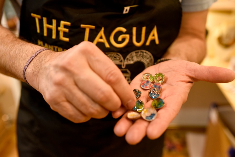 The owner displays colorful acorn shell jewelry on his palm.