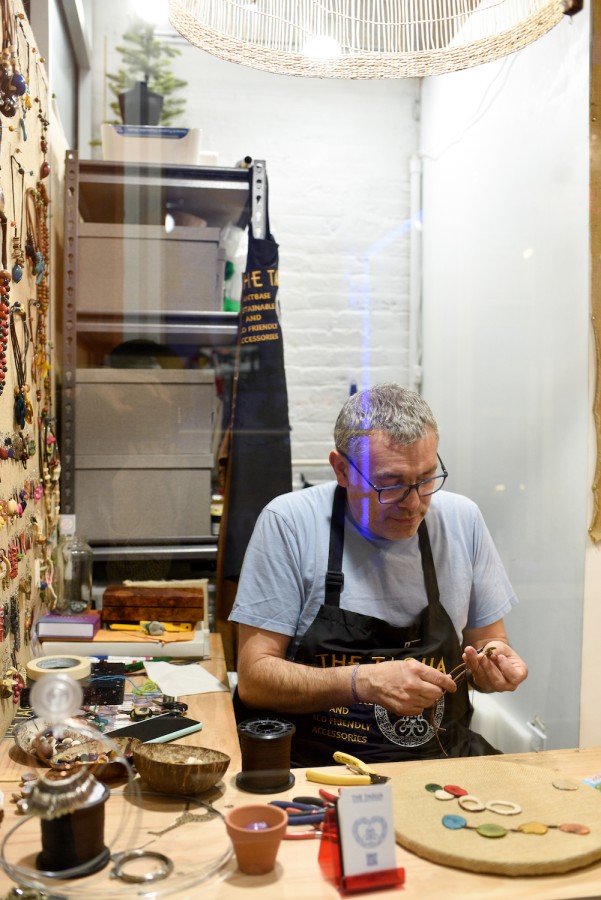 Tagua owner Daniel Neisa sits in his shop’s workspace and works on creating his jewelry.