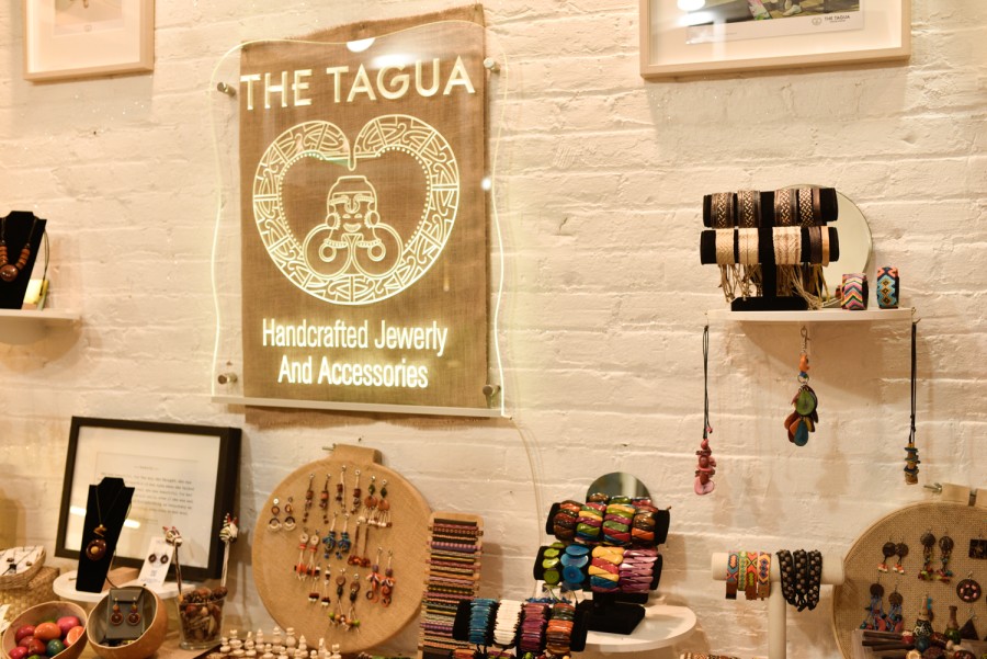 A picture of the L.E.D. Tagua sign inside the shop. Displayed below are owner Daniel Neisa’s jewelry creations.