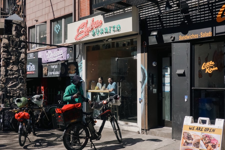 The exterior of Electric Burrito, which has a neon sign against a white background that reads “Electric Burrito.”