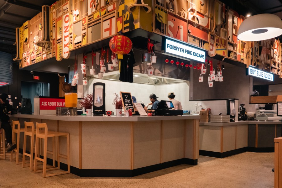 The interior of Forsyth Fire Escape. In the foreground is a bar area with chairs. In the background is a kitchen area with ceilings decorated with Chinese ornaments, such as lanterns.