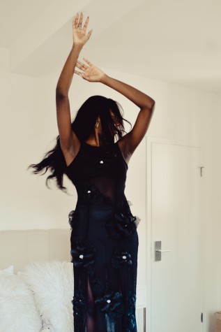 Samantha Harper, founder of Harper Collective, dances on her bed. She is wearing the superbloom dress in noir.