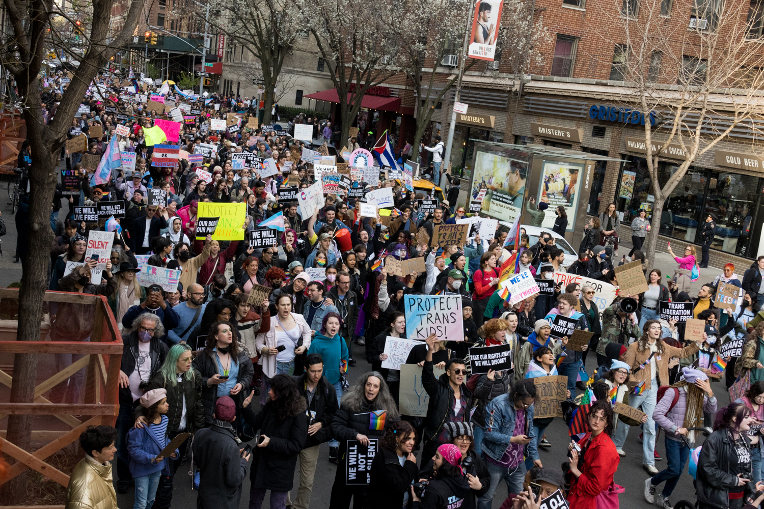 A large crowd of protesters march down University Place holding signs with text like “Protect Trans Kids!” and “Trans Liberation Sets us Free.”