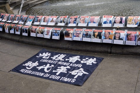 Posters with the names and photos of Hong Kong political prisoners stuck to the rim of the fountain in the center of Washington Square Park. A banner that says “Liberate Hong Kong, Revolution of Our Times” in both Chinese and English is placed under the posters.