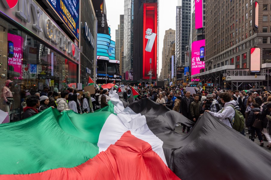 The flag of Palestine is unfurled by a group standing in a crowd in Times Square.