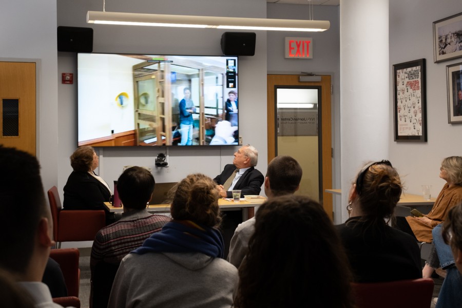 Yevgenia Albats shown on the left and David Hoffman shown on the right both watching a video of Washington Post reporter Evan Gershkovich locked in a glass cell in a Moscow court.