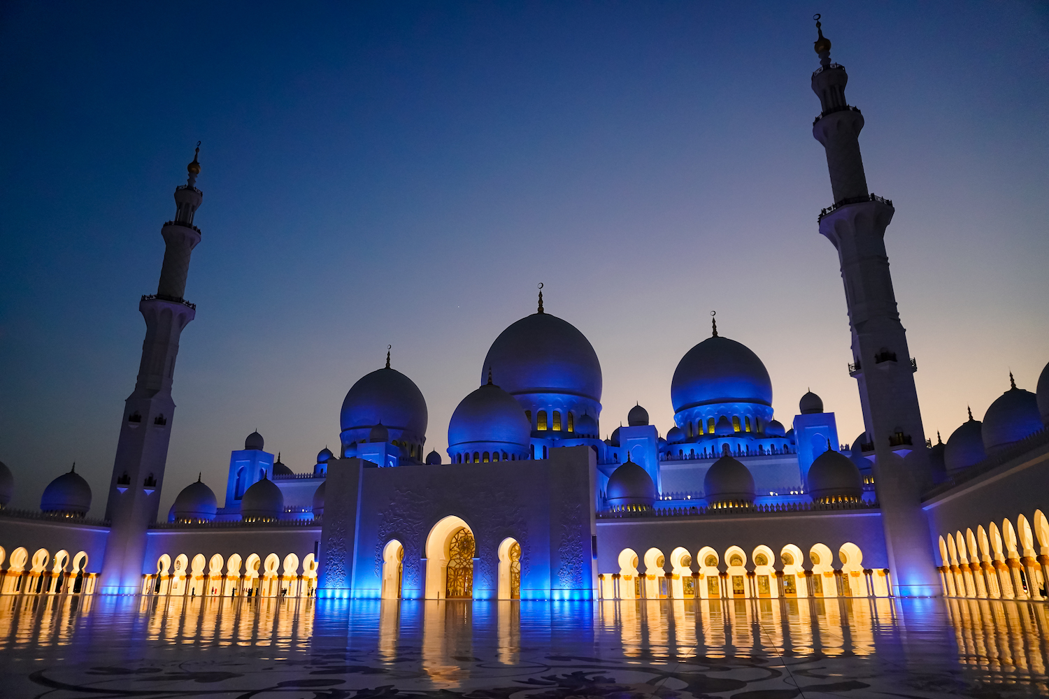 The Sheikh Zayed Grand Mosque lit up blue at night.
