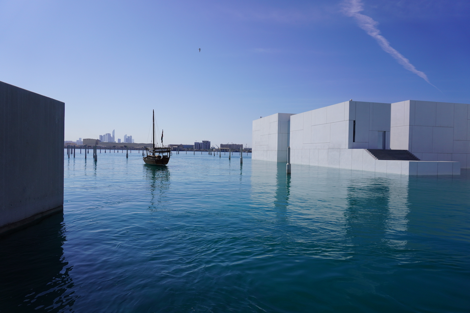 The Louvre Abu Dhabi surrounded by the Persian Gulf, where a boat floats on the turquoise water.3