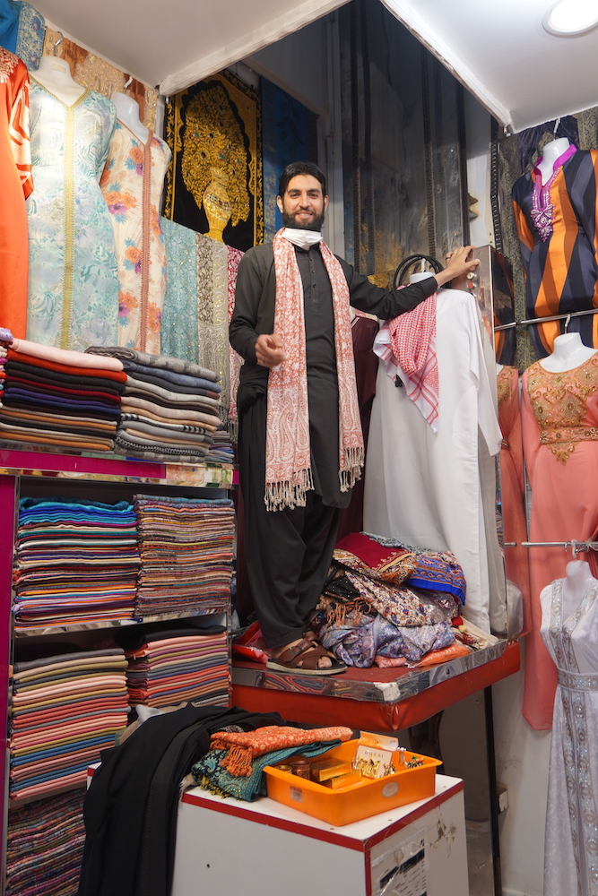 An Afghan shopkeeper takes an elevator up to get abayas.