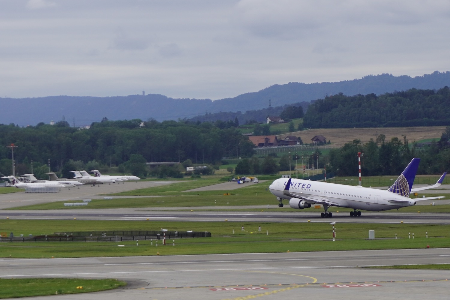 A United Airlines aircraft taking off from the runway at the Zurich Airport in front of the Swiss Alps.