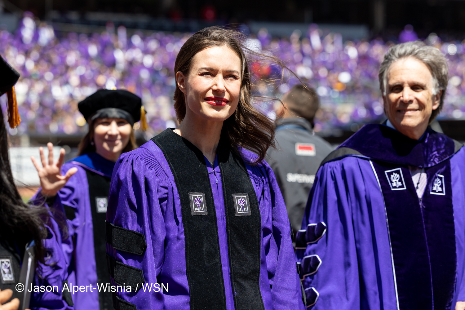 Finnish Prime Minister Sanna Marin walking through a packed Yankee Stadium wearing a purple robe.