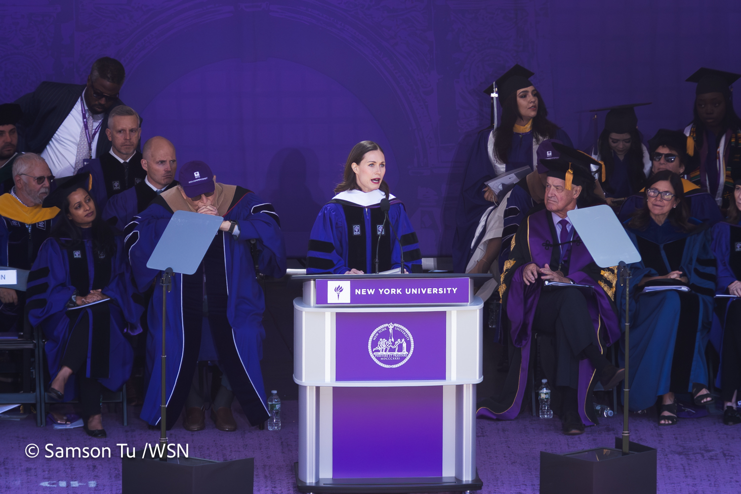 Finnish Prime Minister Sanna Marin delivers her address to the crowd behind a purple podium with a white N.Y.U. emblem and text that read "New York University."
