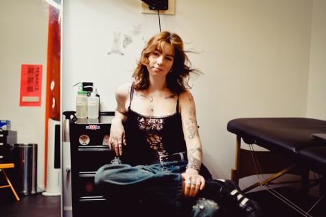 Ella Bowie sits in her Brooklyn tattoo studio. She faces the camera.