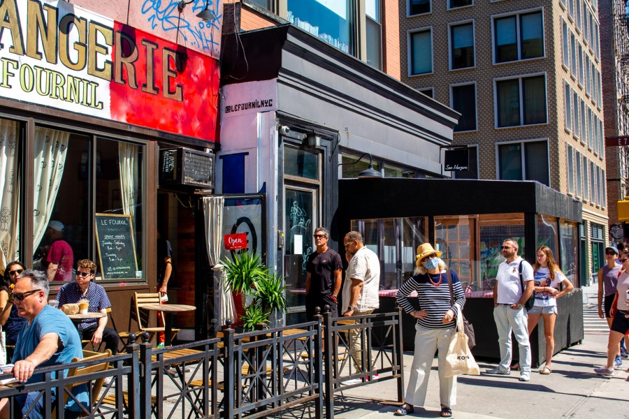 The exterior of Le Fournil bakery. A banner with white text reads “Boulangerie” in blue, red and white, the color of the French flag, sits above the entrance.