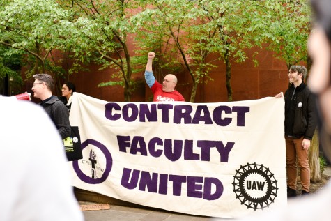 Three people hold a banner that reads “Contract Faculty United.” One of them has his fist raised in the air.