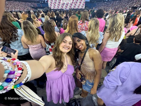 Natalie Thomas and Manasa Gudavalli take a selfie in the middle of the Gillette Stadium. Natalie wears a light purple dress and Manasa wears a cream crop top and a pair of denim shorts.