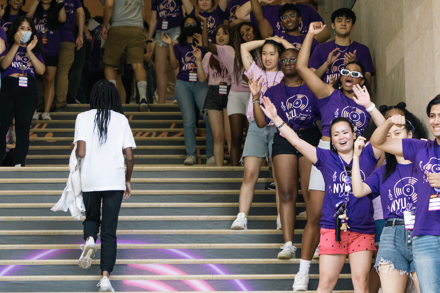 N.Y.U. Welcome Week ambassadors stand on the steps in the lobby of the Kimmel Center for Student Life waving and cheering to passersby.