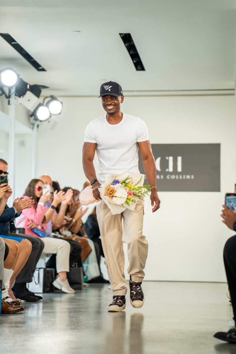 Chuks Collins walks down the runway holding flowers.