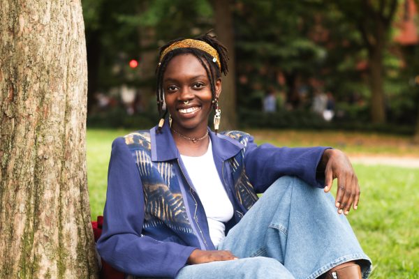 Brown Sugar Brilliance's founder, Mae Monga, sits on the grass while smiling.