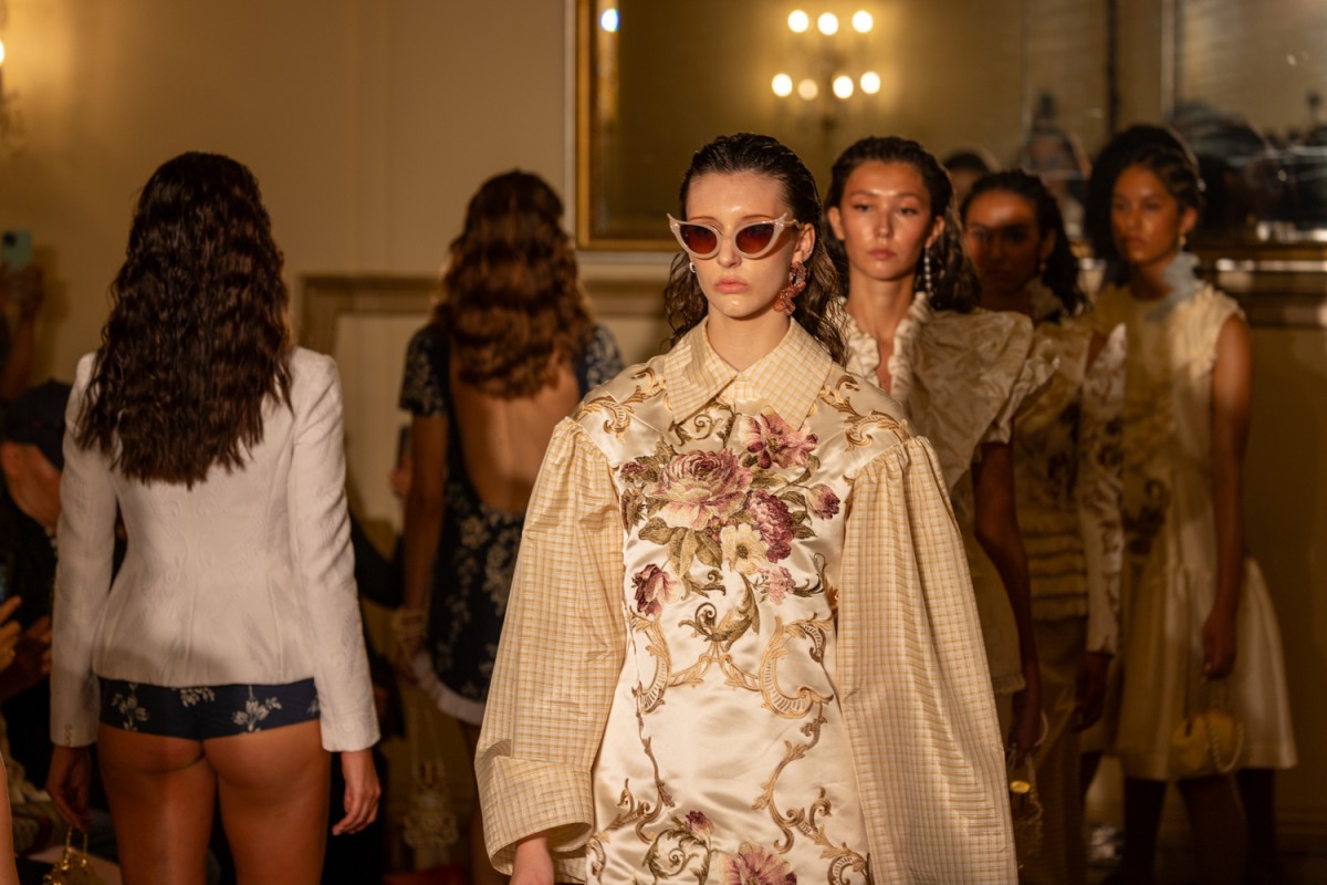 A model wears a beige floral shirt.