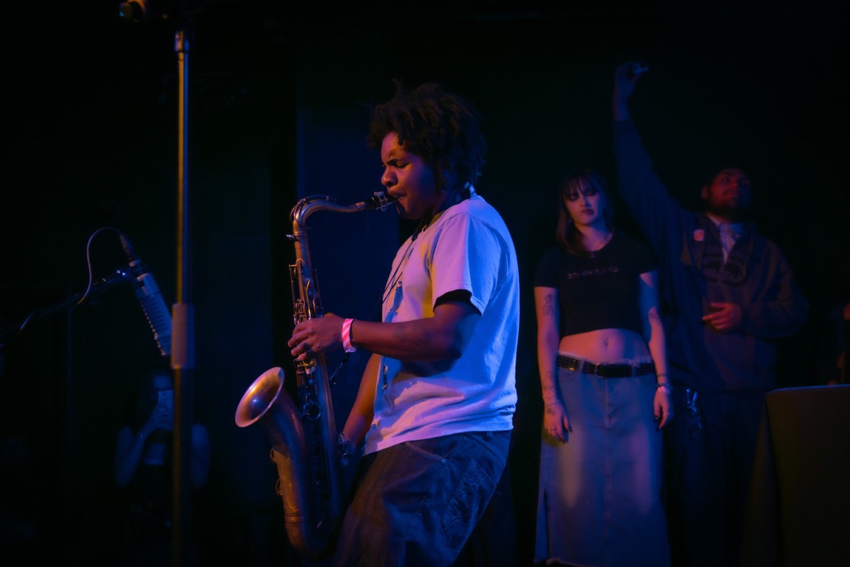 Artist Diz playing a saxophone on stage.