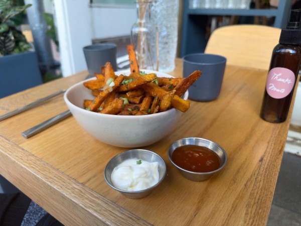 A bowl of sweet potato fries with two dipping sauces on the corner of an outdoor table at Ruby’s Cafe.