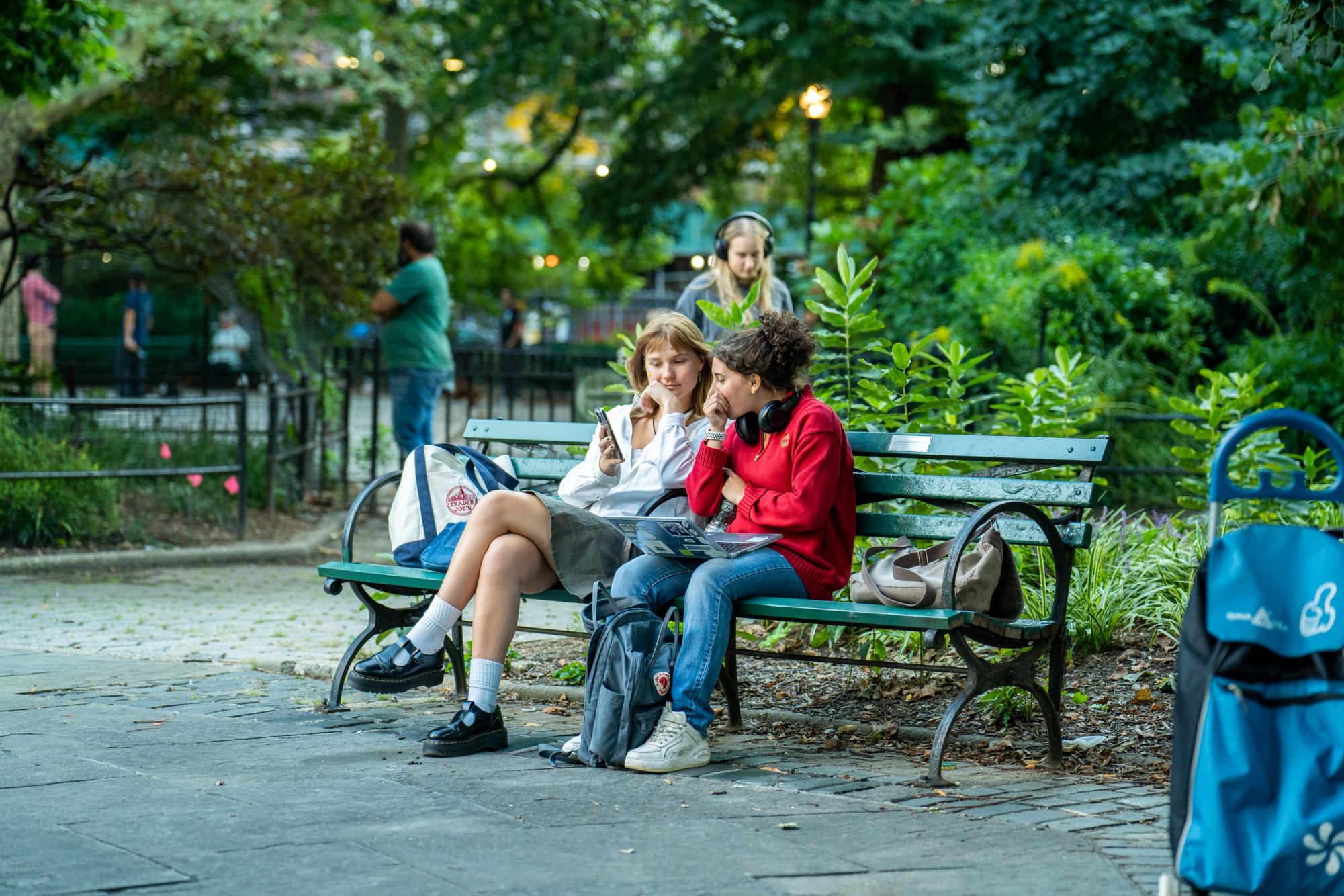 Two people talk on a park bench in Stuyvesant Square Park.
