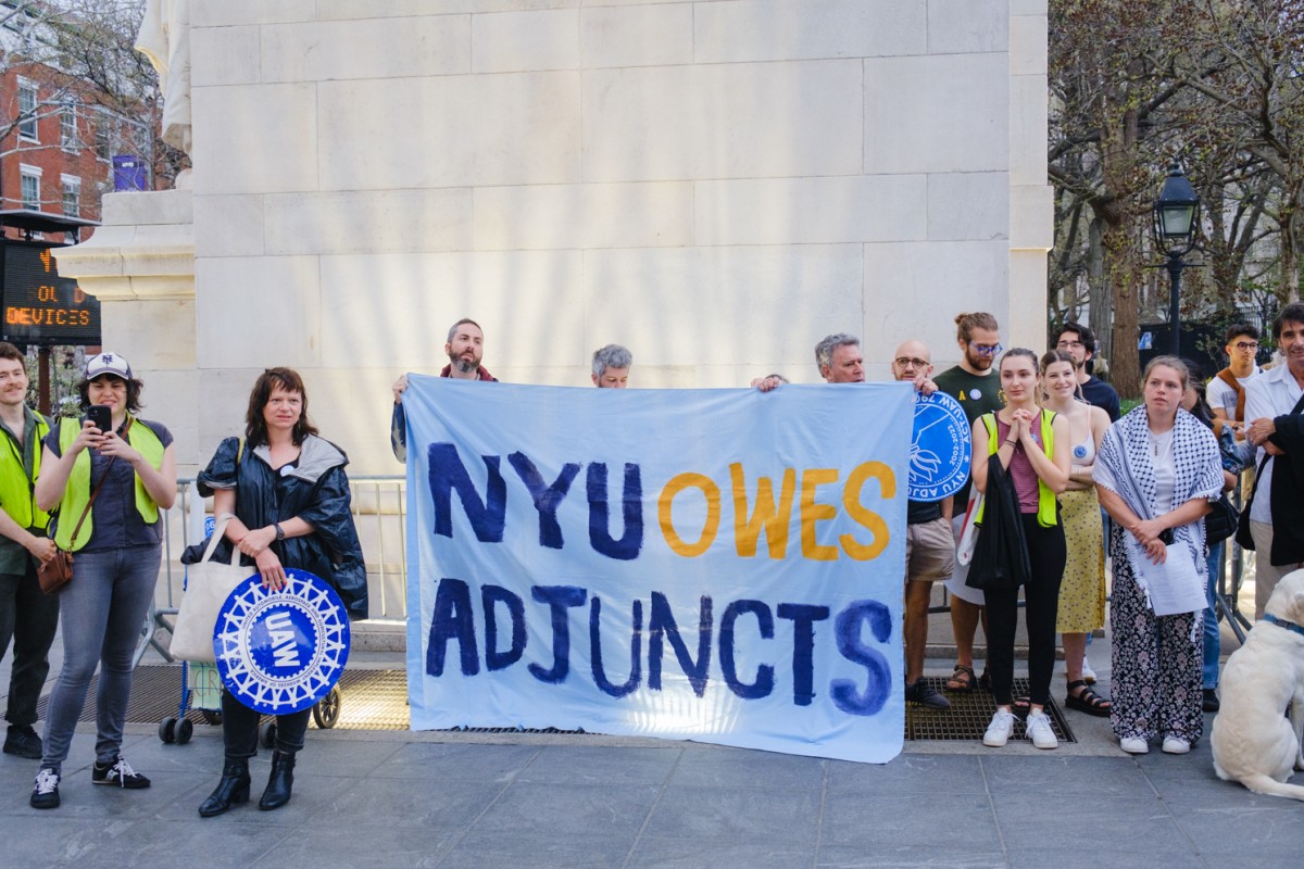 Protesters walk down University Place holding large signs that read ”N.Y.U. OWES ADJUNCTS” and “UNION POWER.”