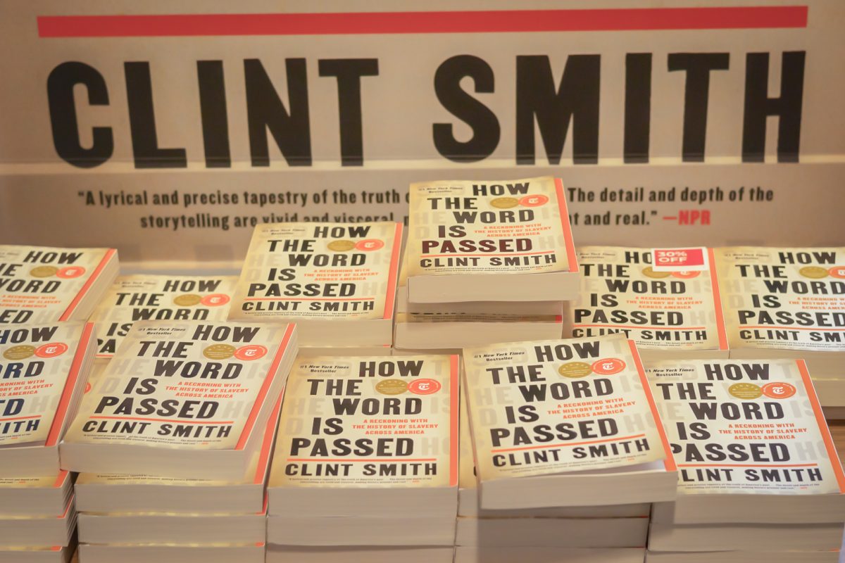 A+pile+of+Clint+Smith%E2%80%99s+book+%E2%80%9CHow+the+Word+is+Passed%E2%80%9D+displayed+in+the+N.Y.U.+Bookstore.+Behind+the+pile+is+a+board+with+Smith%E2%80%99s+name+written+on+it.