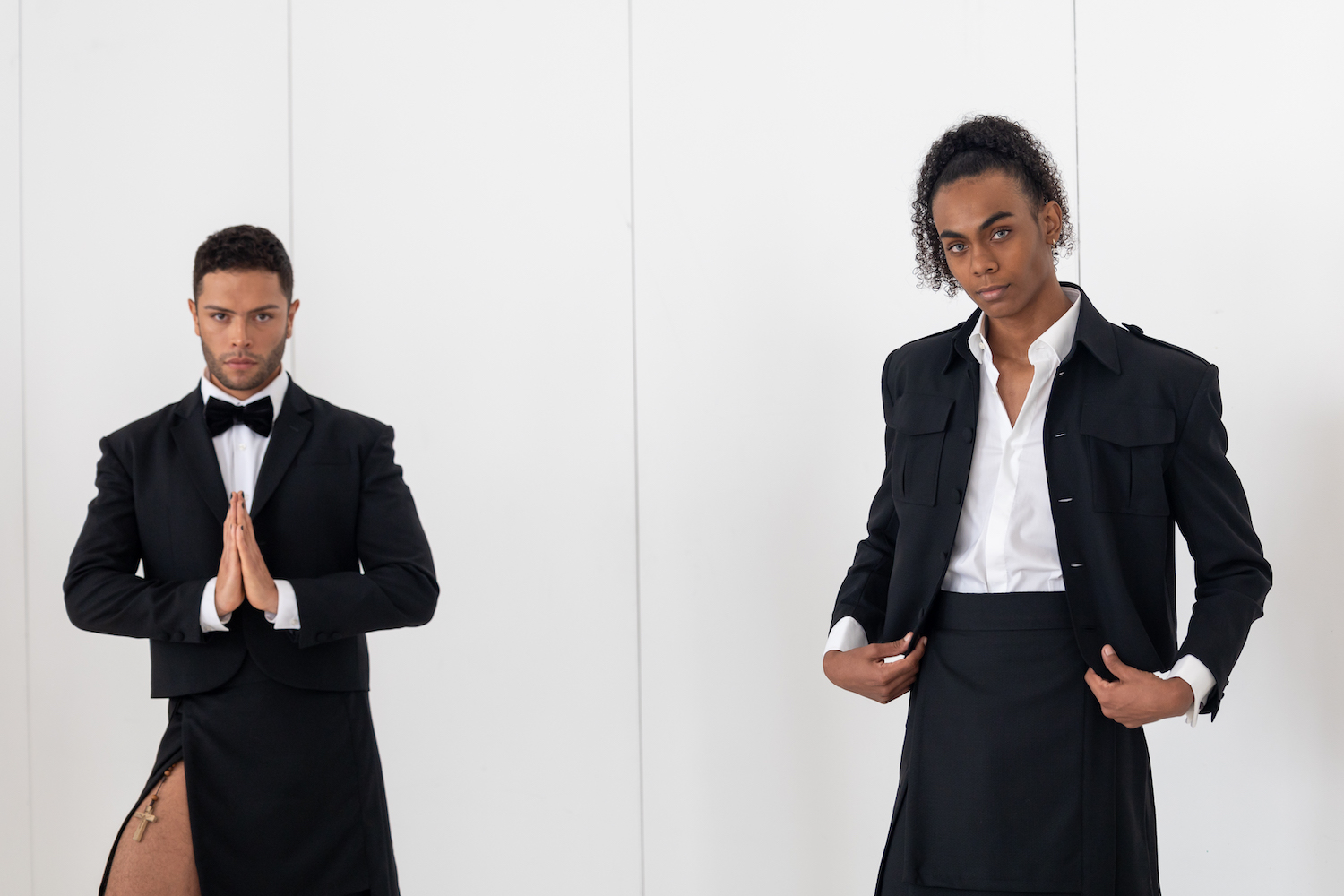 Two models wearing black blazers over white dress shirts pose together near a wall of the showroom. The models are wearing clothes from TERRY SINGH.