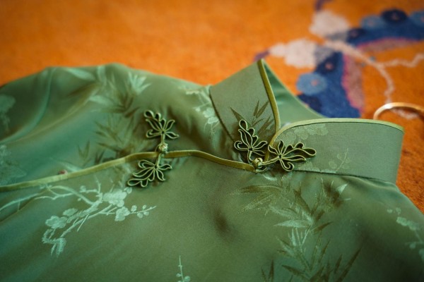 A green summer-style cheongsam featuring traditional Chinese bamboo and plum blossom patterns.