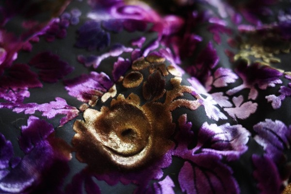 A Devore cheongsam, laid out. It is black and purple, with some gold too.