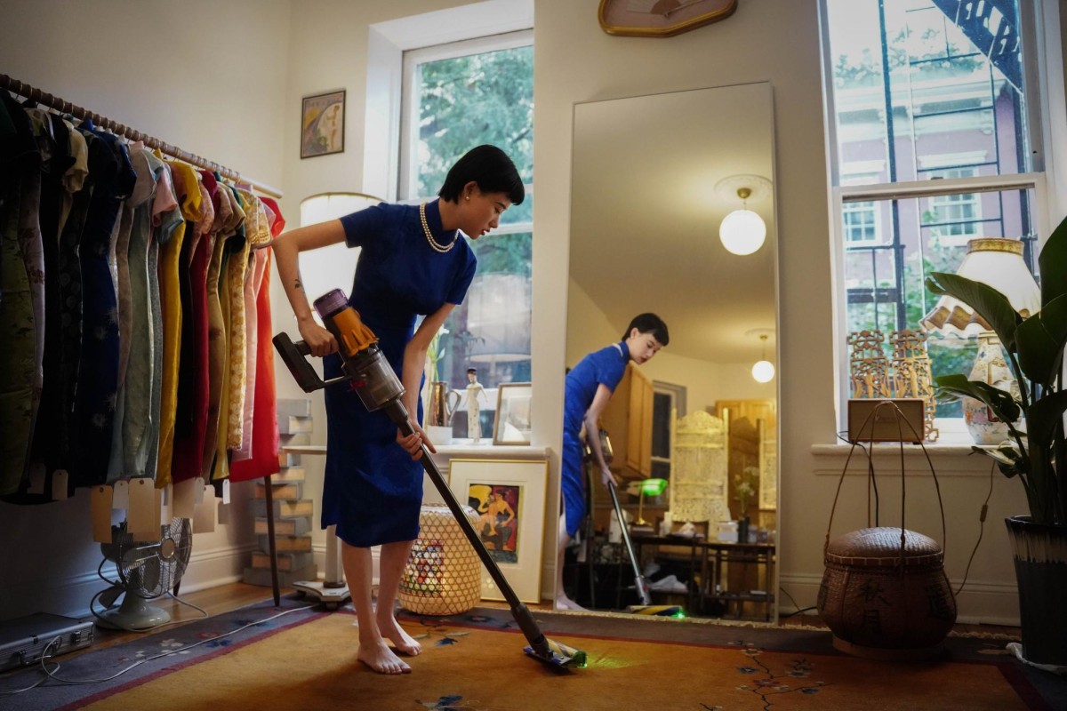 Guo uses a vacuum cleaner to clean the vintage carpet in her cheongsam studio.