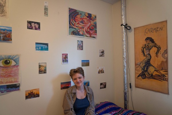 A person sitting in front of a wall decorated with photos and drawings.