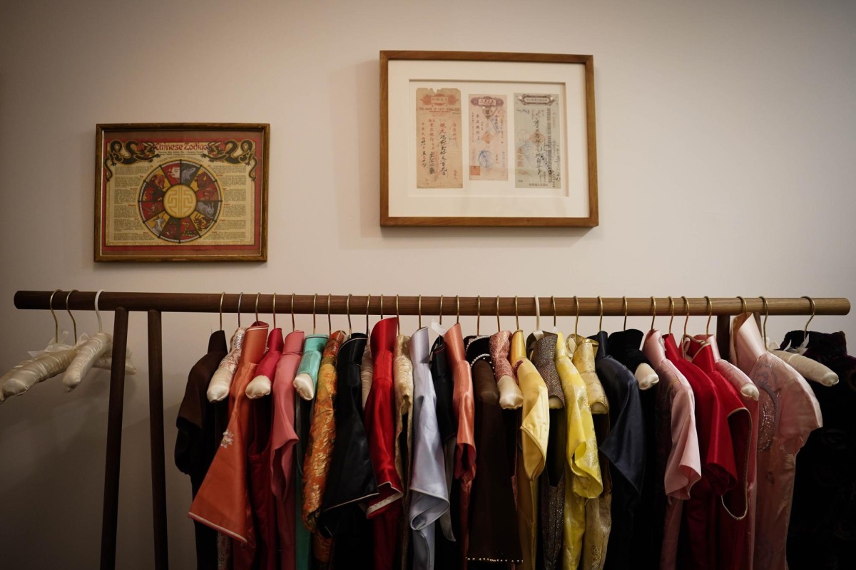 Several dresses of various colors hang on a wooden rod.