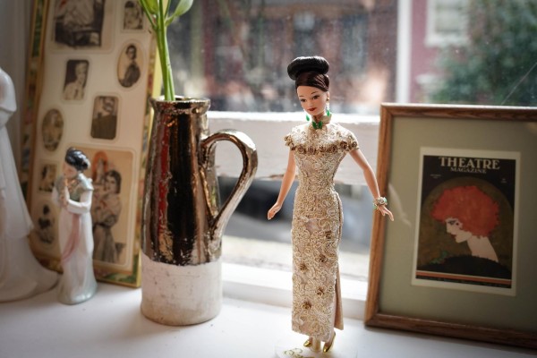 A Barbie doll dressed in a gold and white cheongsam.